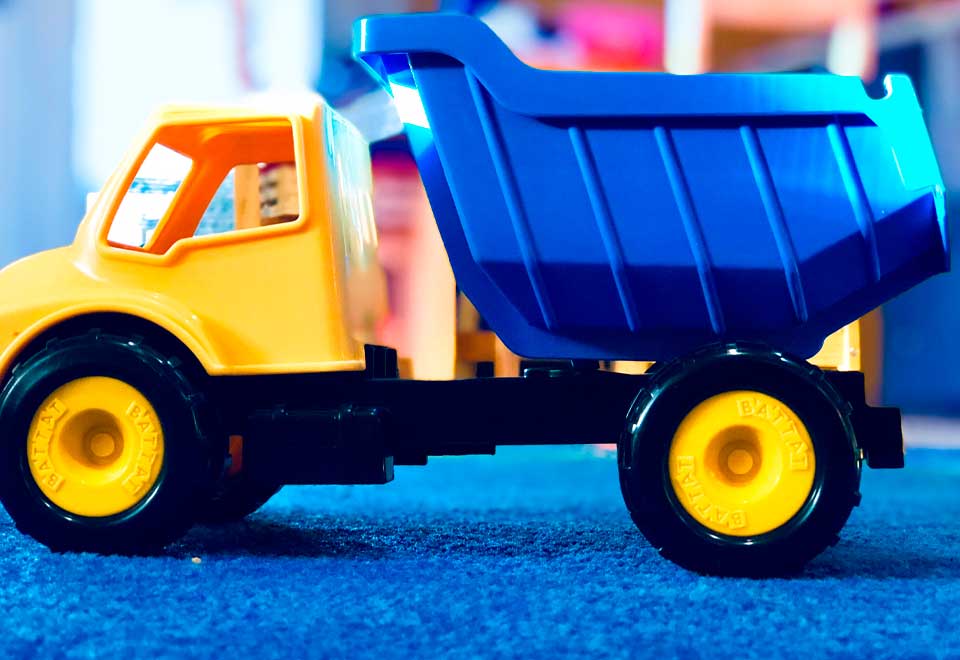 Maquina de construcción le echo tierra en un carro de juguete a un niño